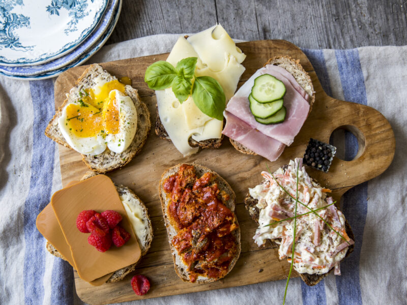 Et skjærebrett i tre med en rekke smørbrød på.