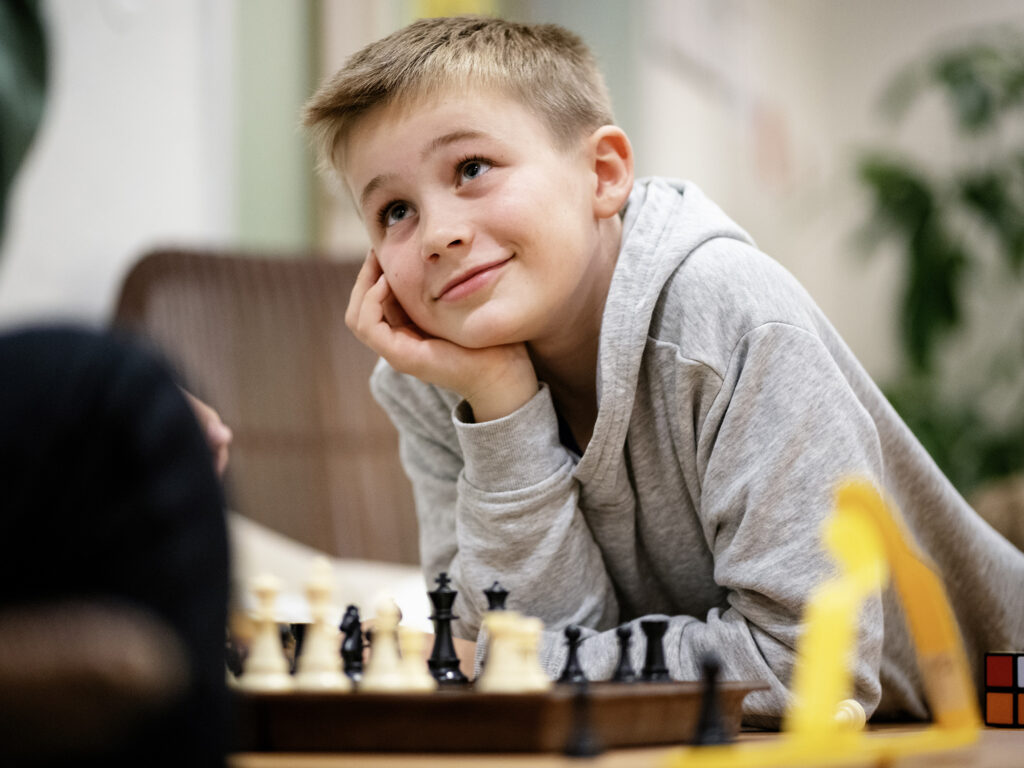 En ung gutt spiller sjakk og ser på mostanderen.