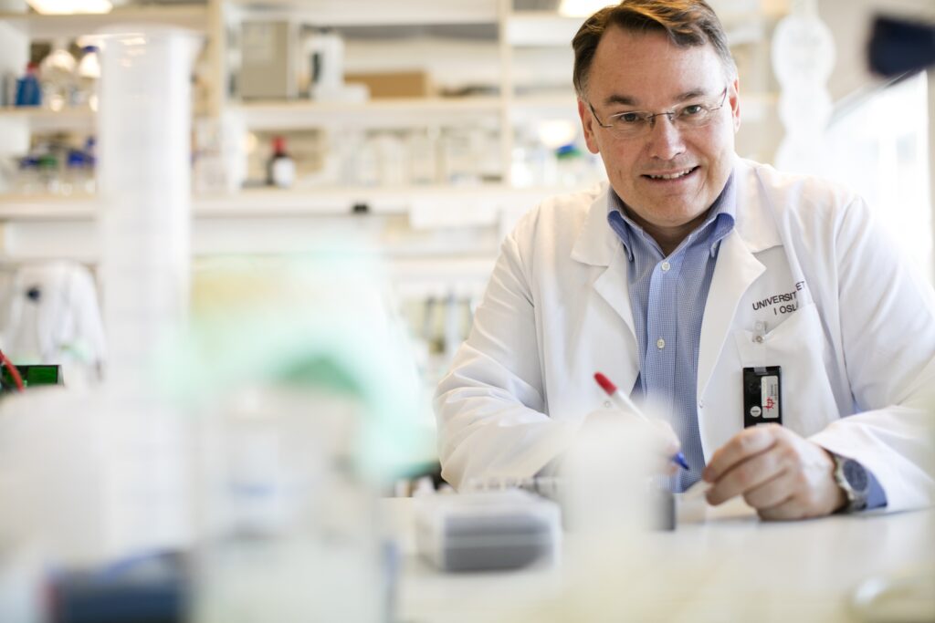 En mann i hvit frakk sitter på et laboratorium