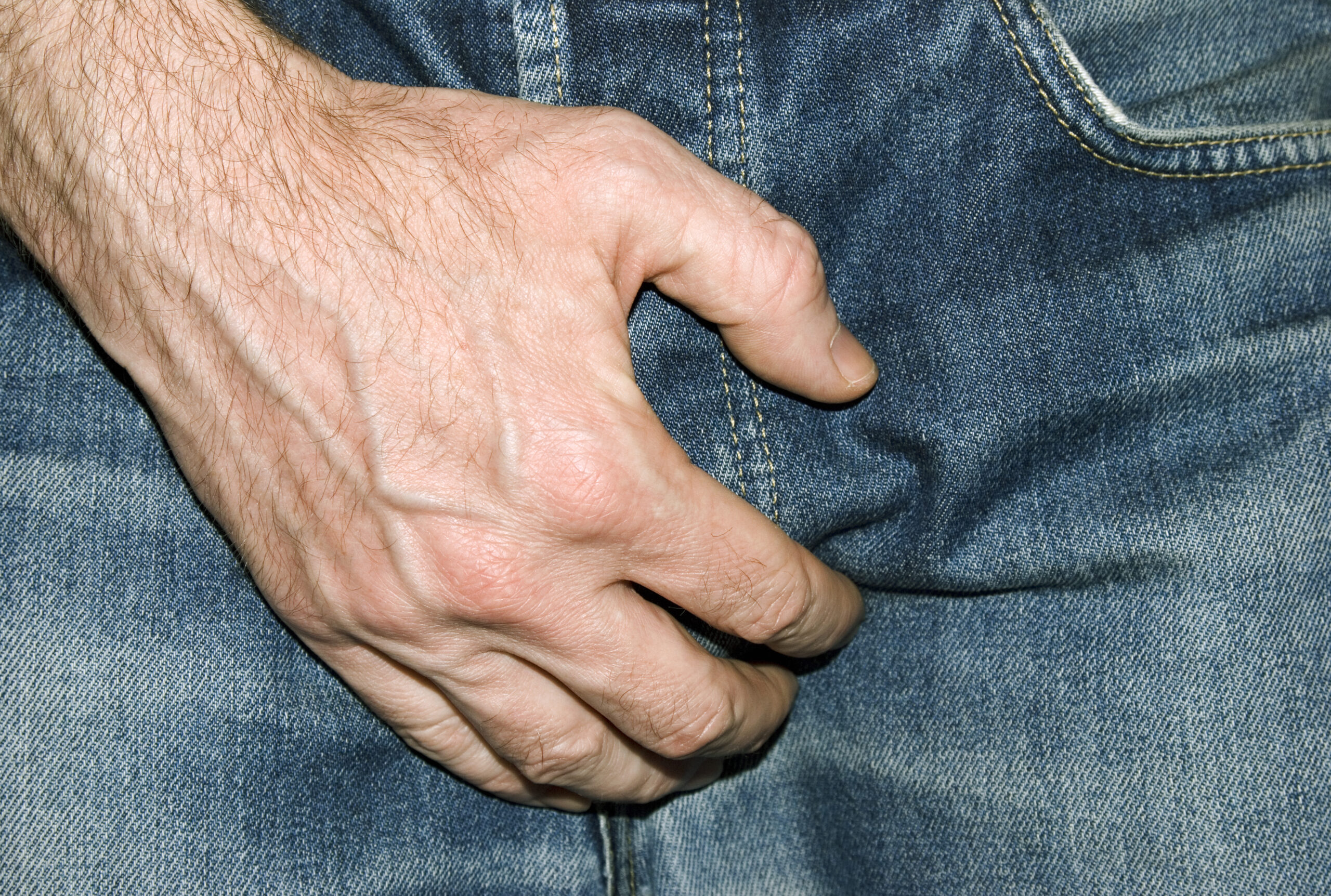 et nærbilde av en persons hånd på jeansen hans.
