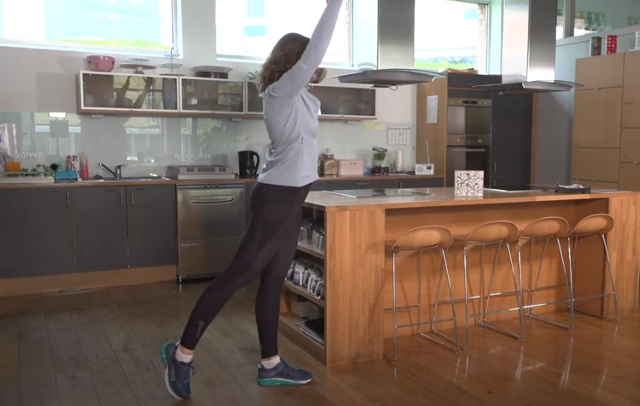 en kvinne som står på et kjøkken med armene i været. trening