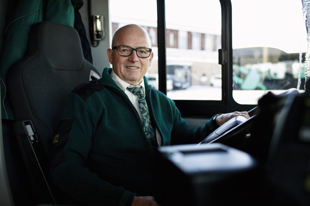 Portrettfoto av Kjell som sitter i førersetet på en buss.
