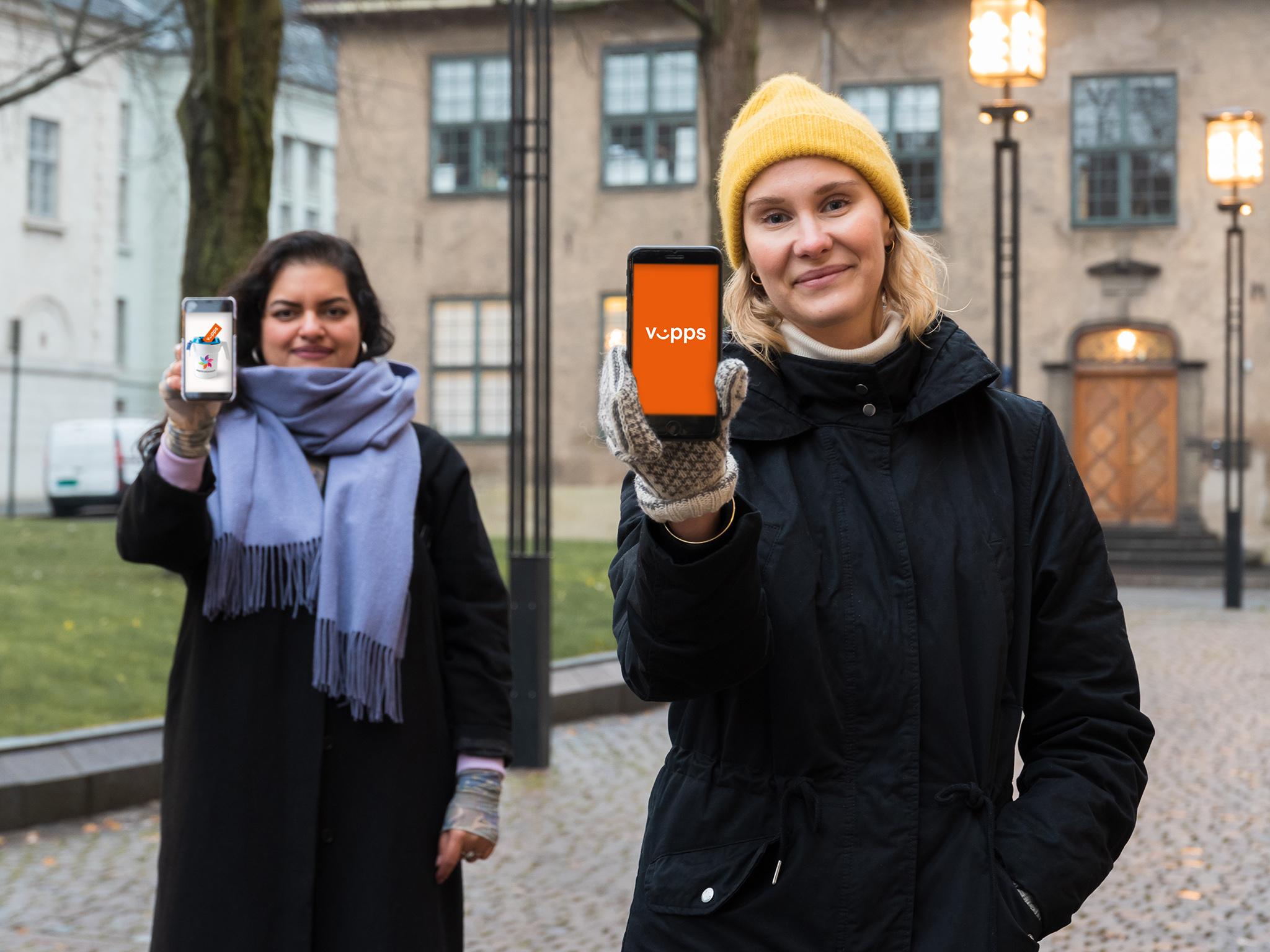 kvinner som holder opp mobiltelefonen foran en bygning.