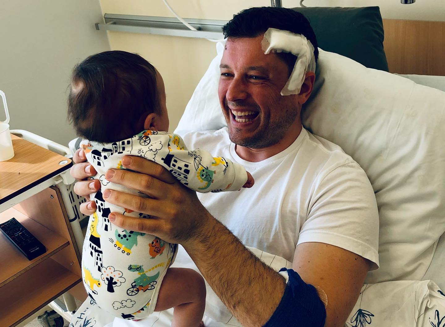 en mann som holder en baby i en sykehusseng.