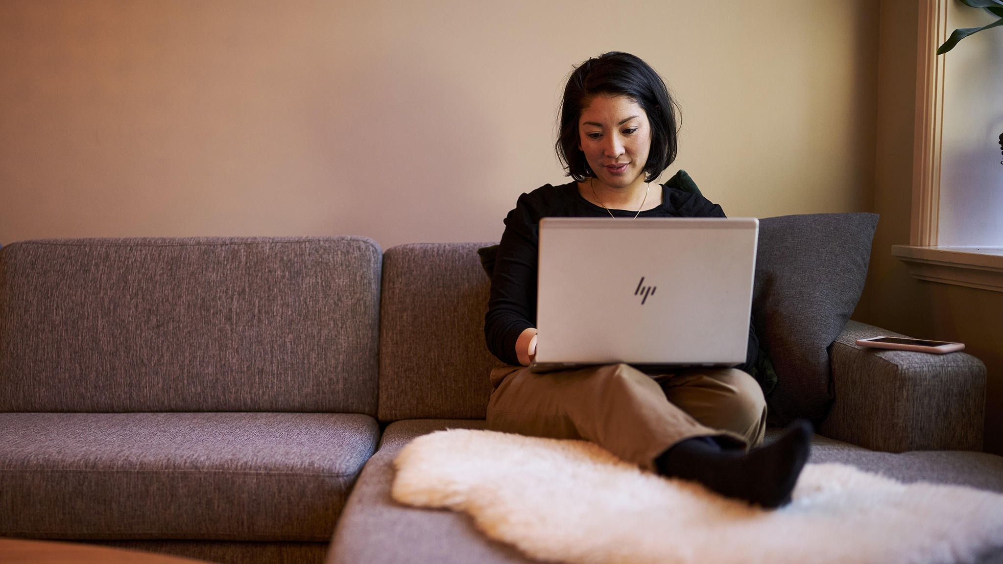 en kvinne som sitter på en sofa med en bærbar datamaskin.