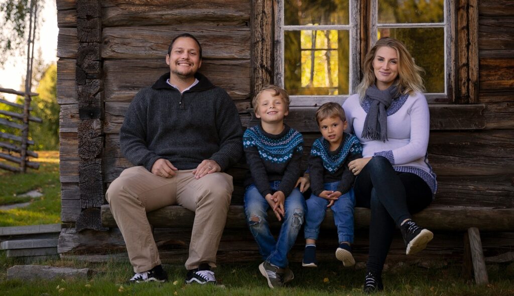 en familie som sitter på en benk foran en tømmerhytte.