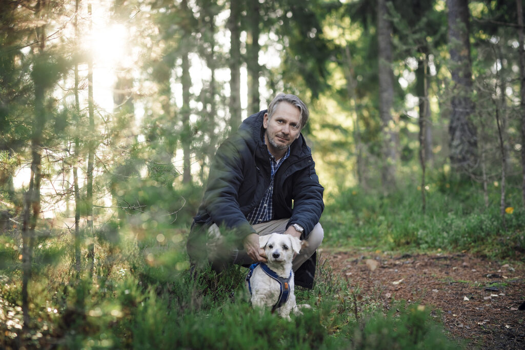 Glenn sitter sammen med hunden sin, Junior, i skogen.