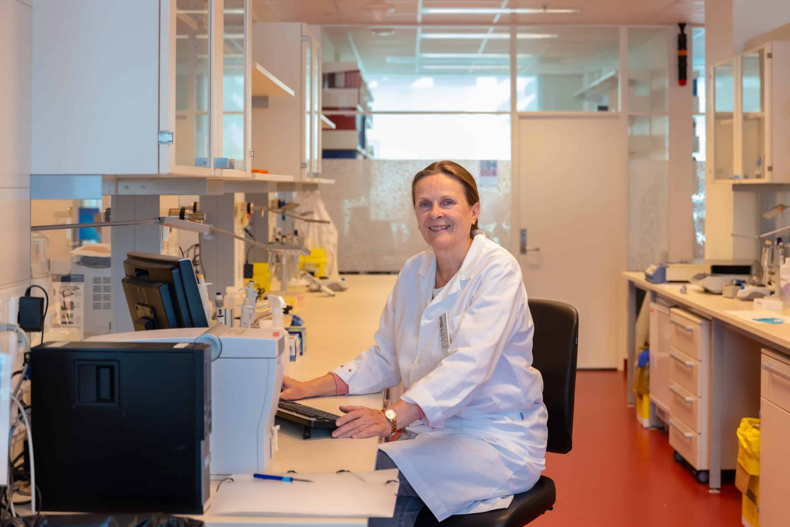 en kvinne som sitter ved et skrivebord i et laboratorium.