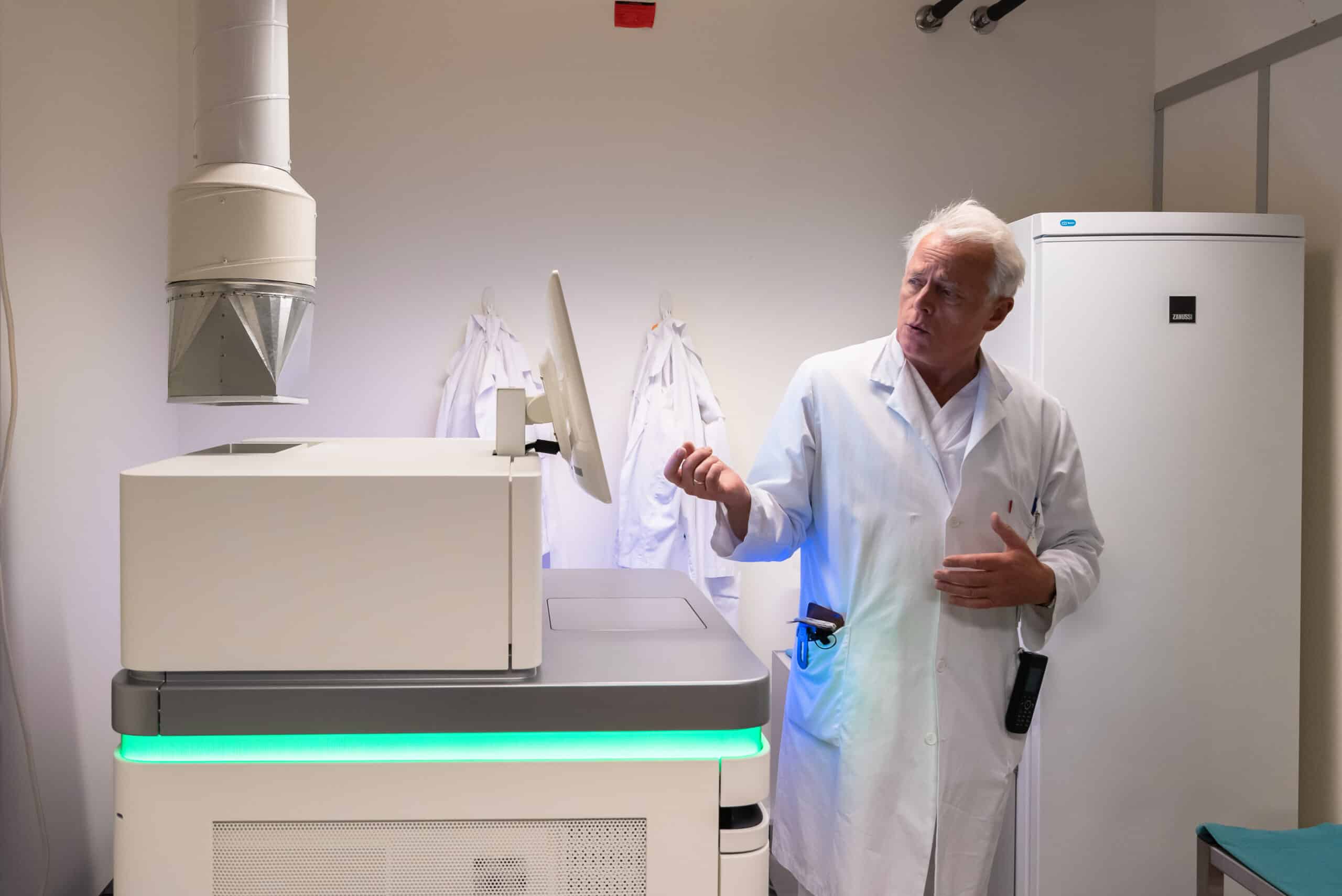 en mann i laboratoriefrakk som står ved siden av en maskin.