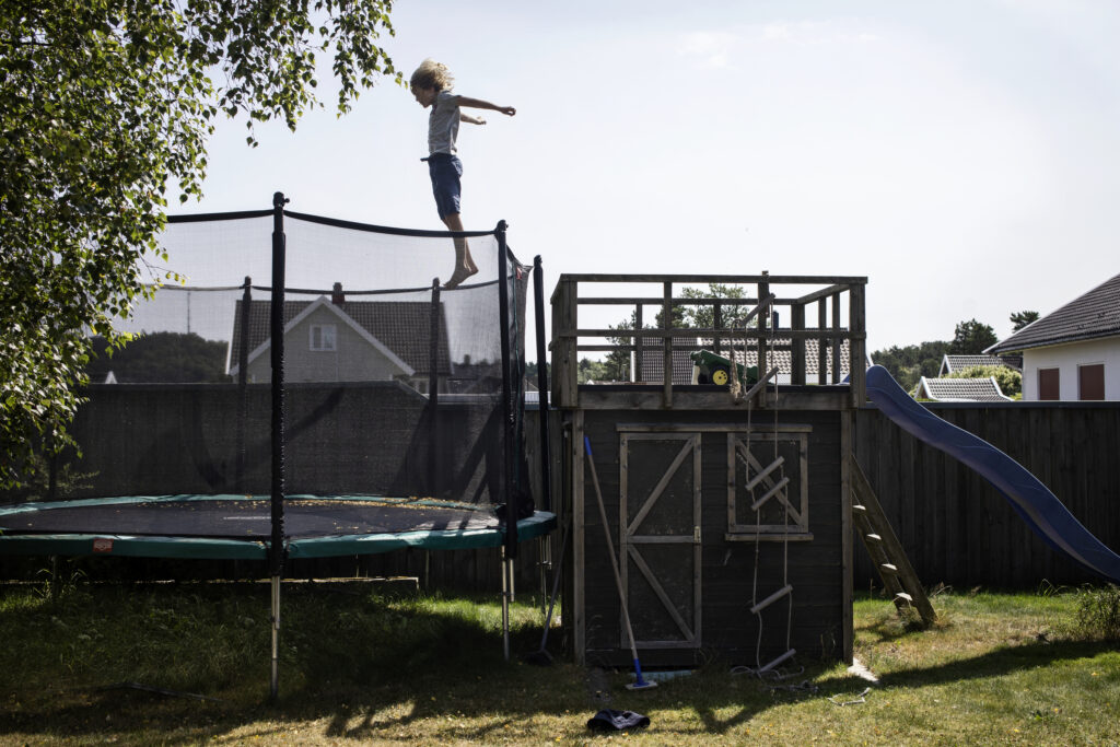 en person som hopper på en trampoline i en bakgård.
