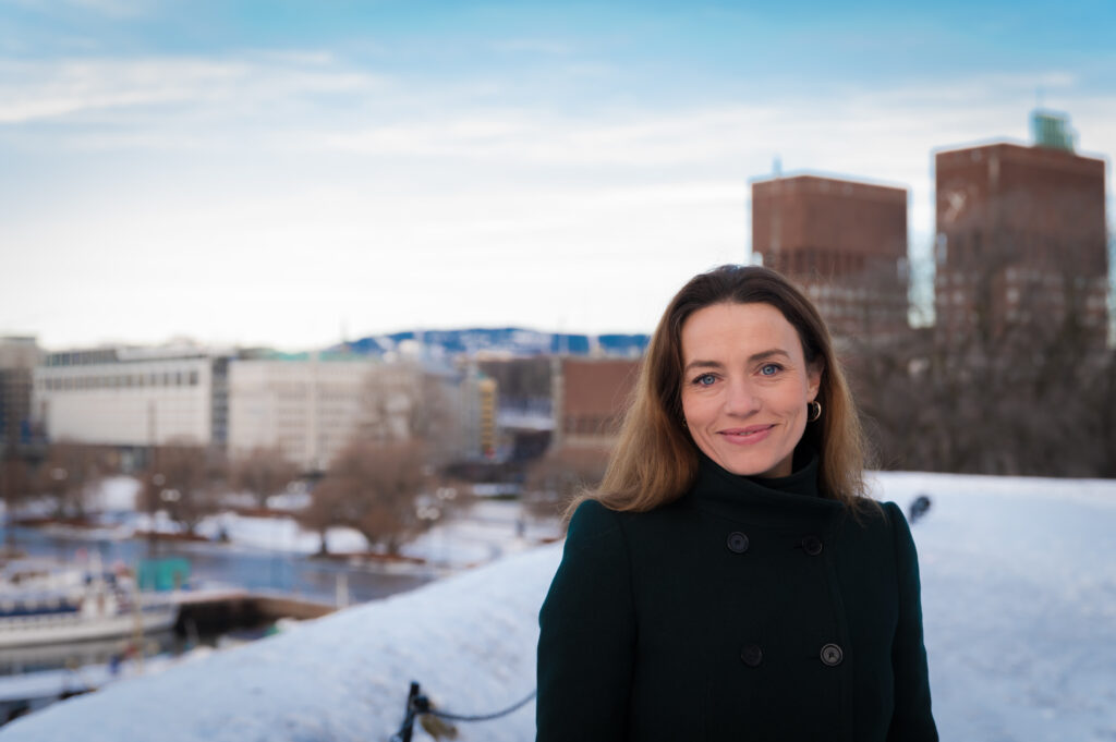 Portrettfoto av Ingrid Stenstadvold Ross med Oslo rådhus i bakgrunnen.