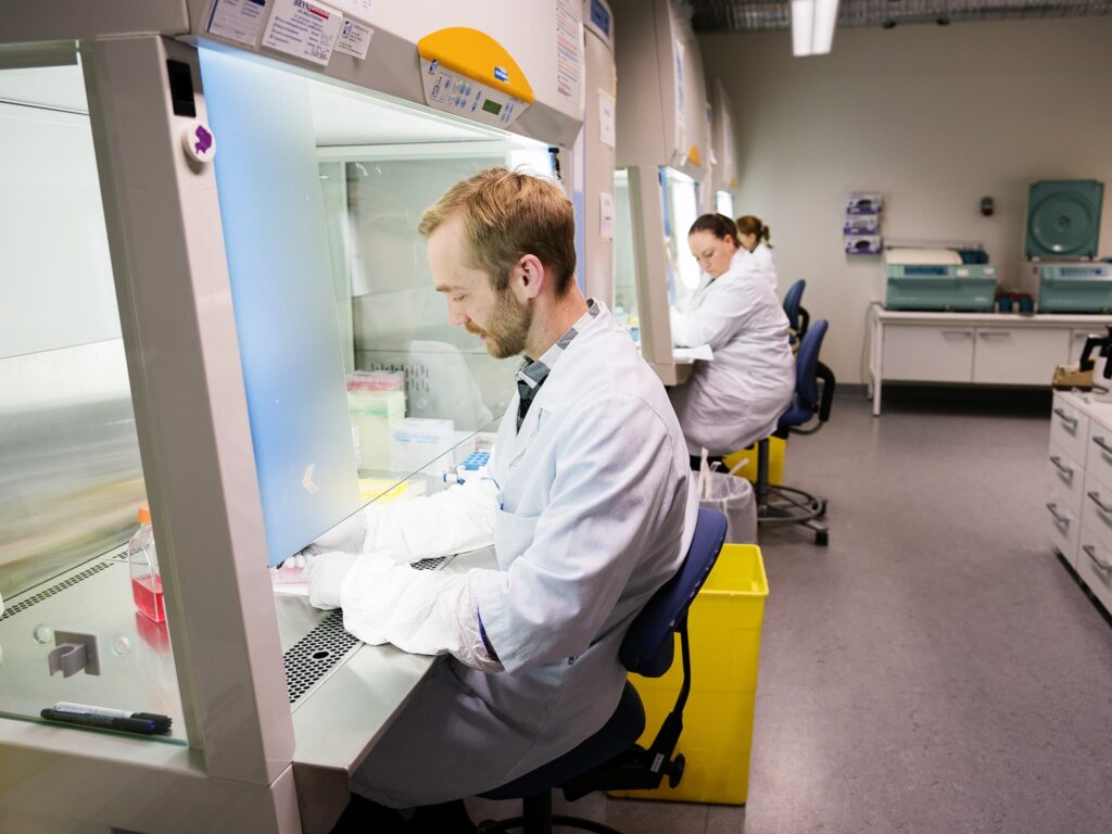 en mann som sitter ved et skrivebord i et laboratorium.