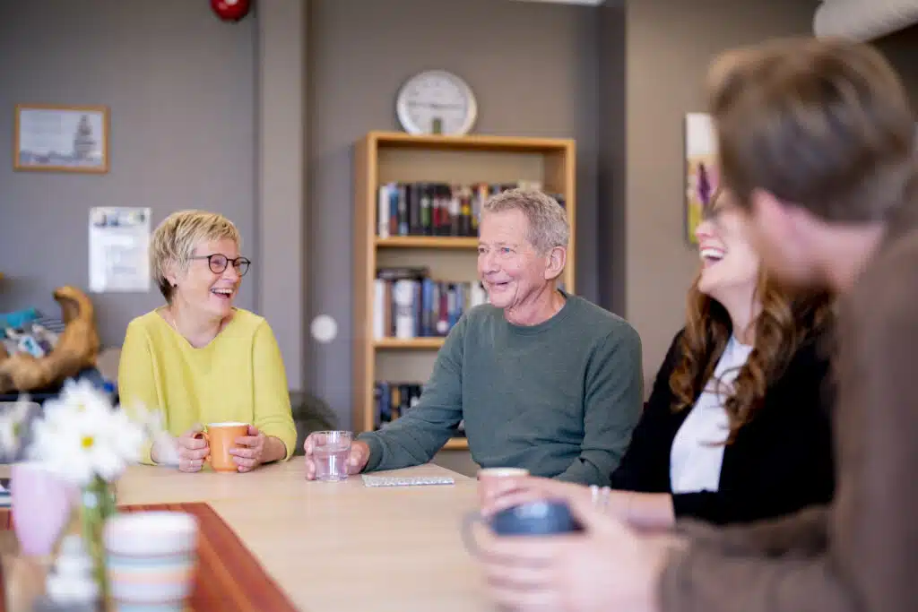 en gruppe mennesker som sitter rundt et trebord.