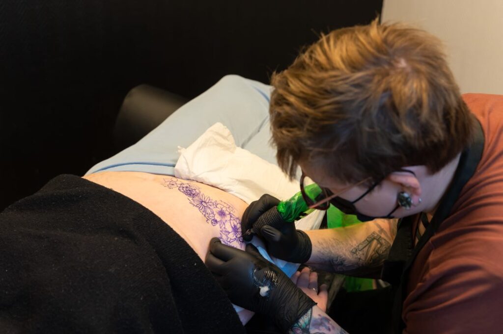 en kvinne som tar en tatovering på opersasjonssåret.