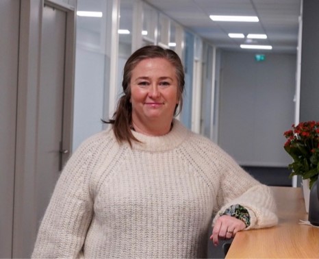 en kvinne i en genser som står på et kontor.