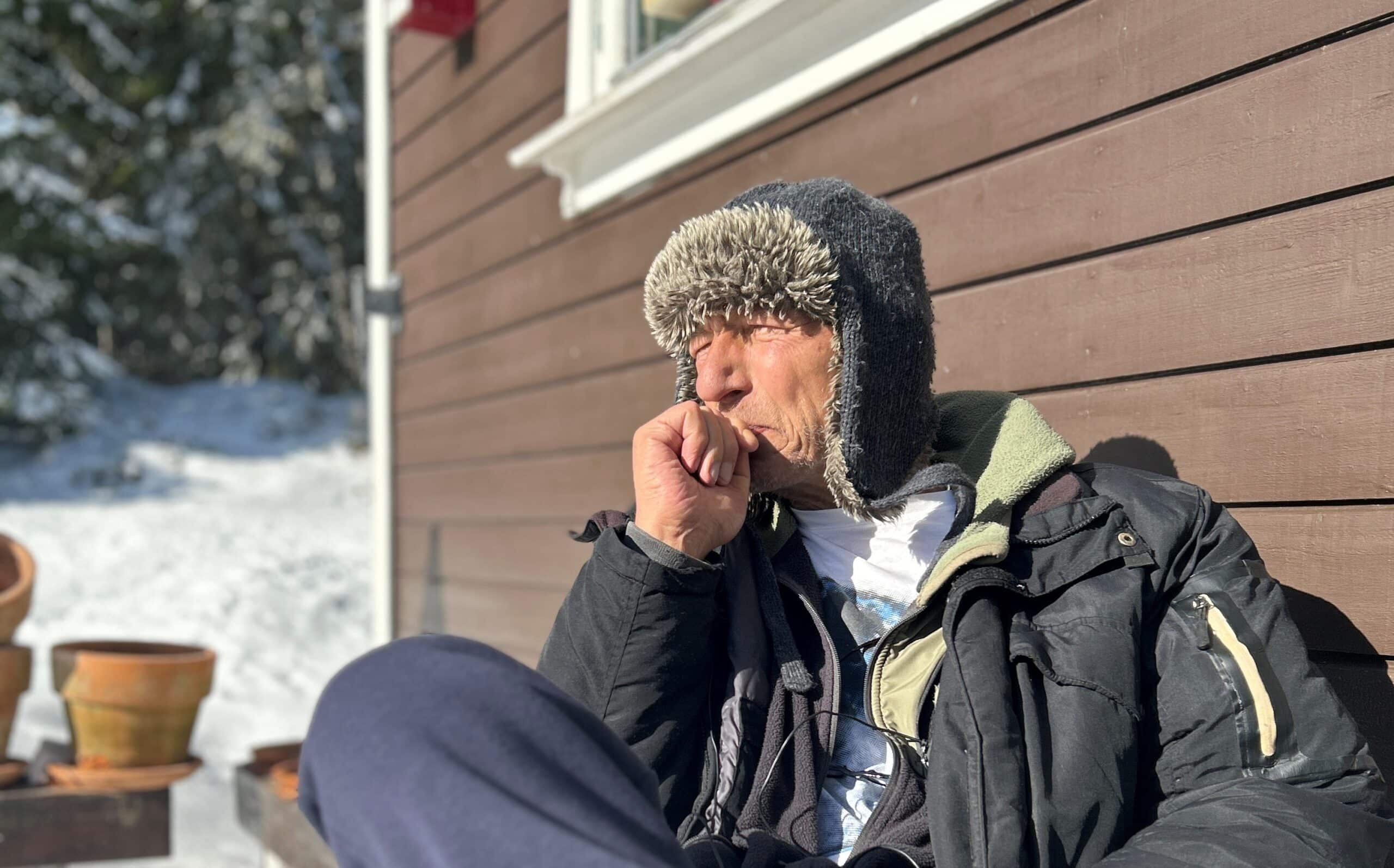 Morten Hansen som sitter på siden av et hus iført hatt.
