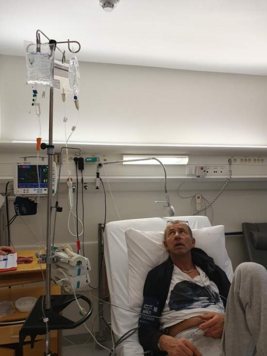 en mann som ligger i en sykehusseng på et rom.