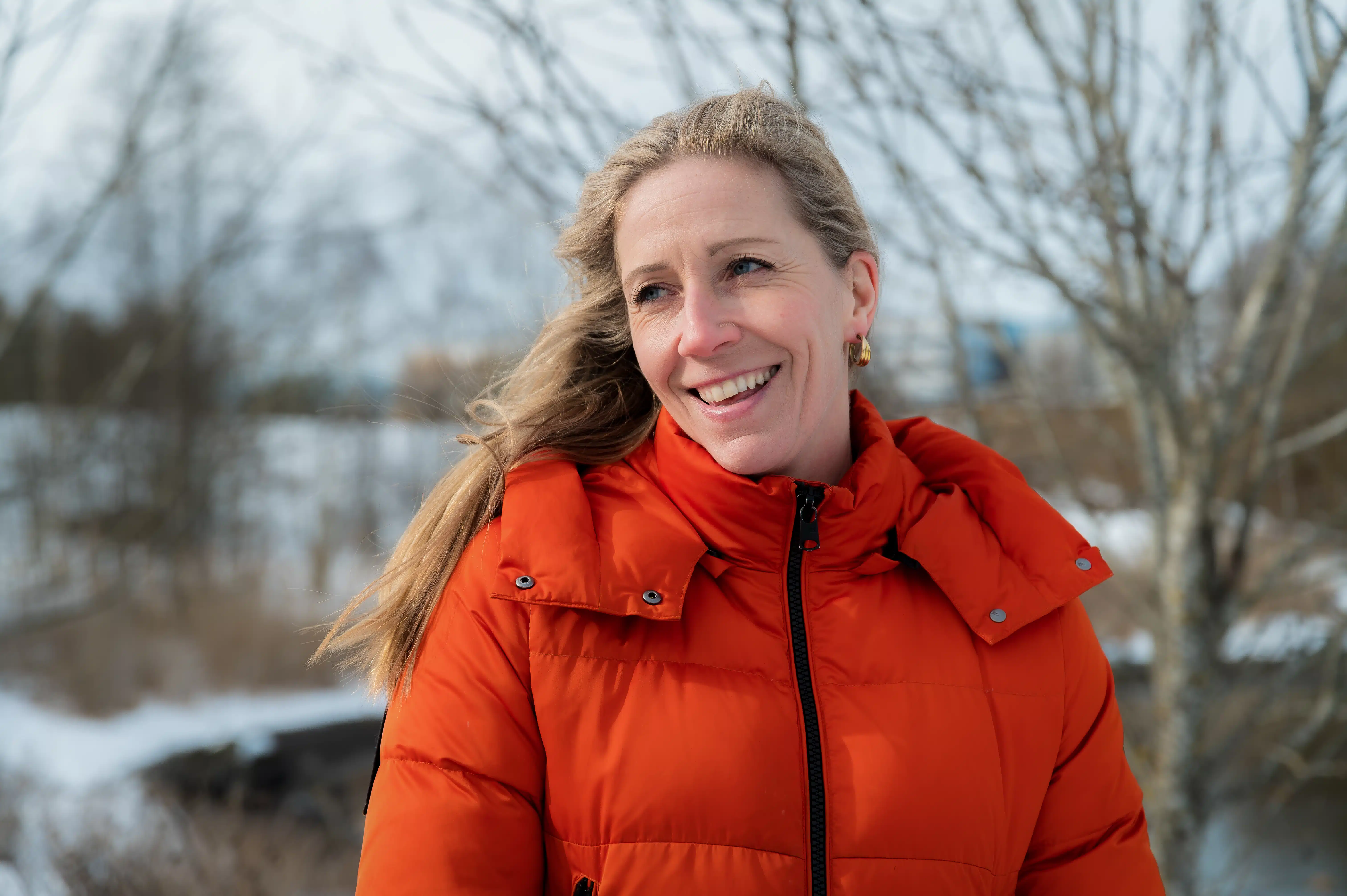 Nina Jensen i en oransje jakke smiler til kameraet.