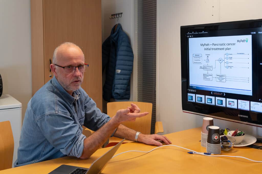 Professor Stein Kaasa foran en dataskjerm.