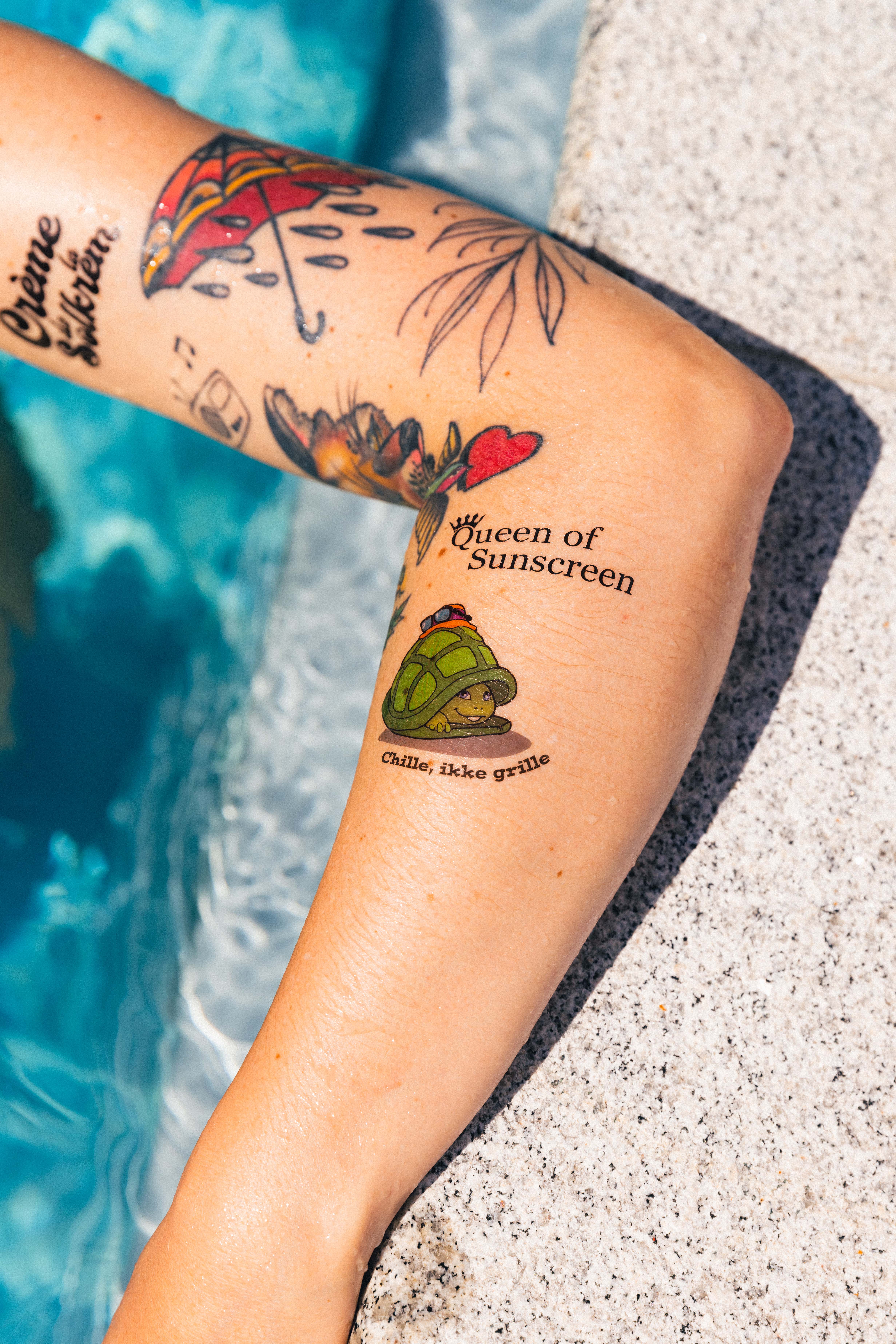 en person med en tatovering på armen ved siden av et svømmebasseng.