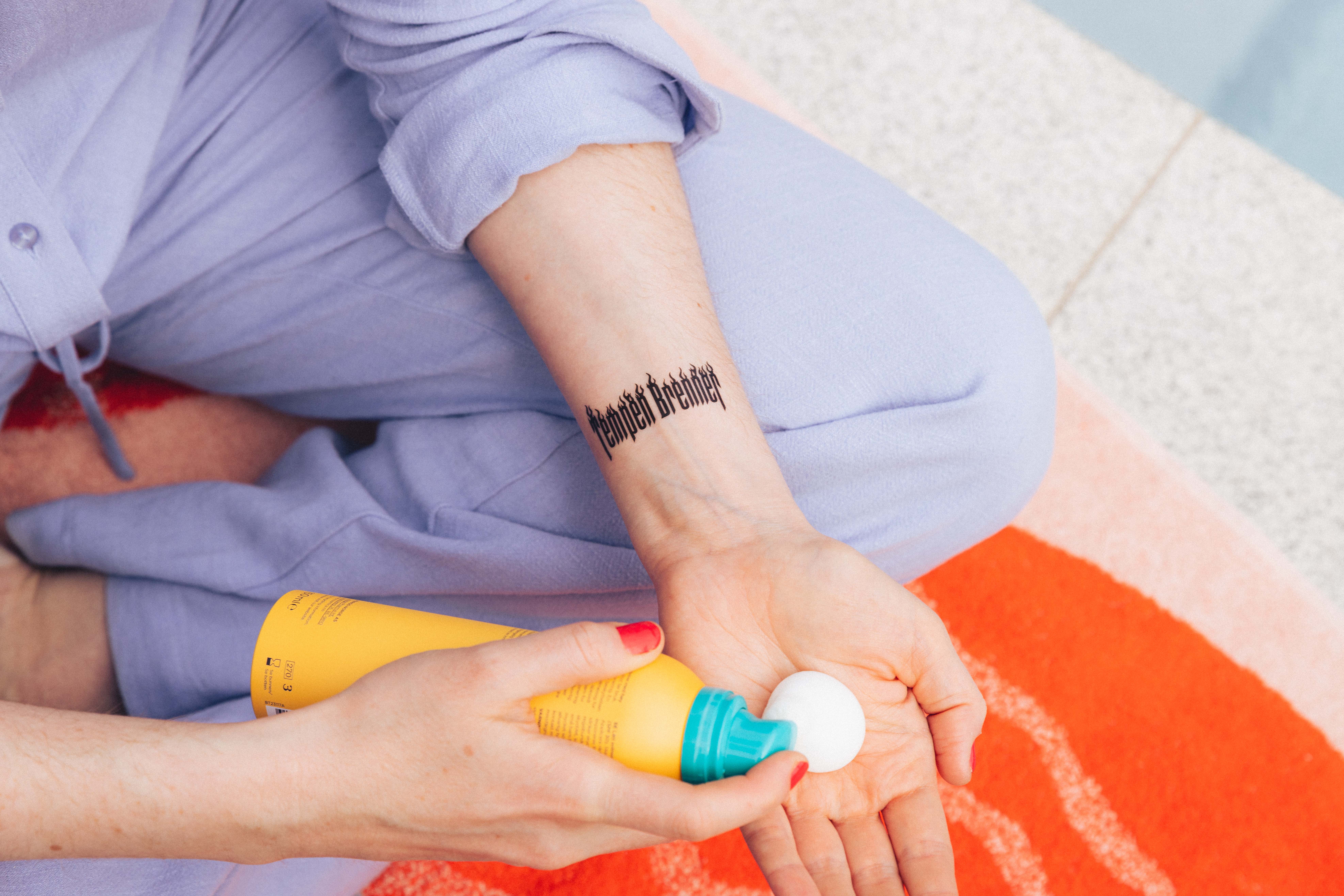 en kvinne med en tatovering på armen som holder en tåteflaske.