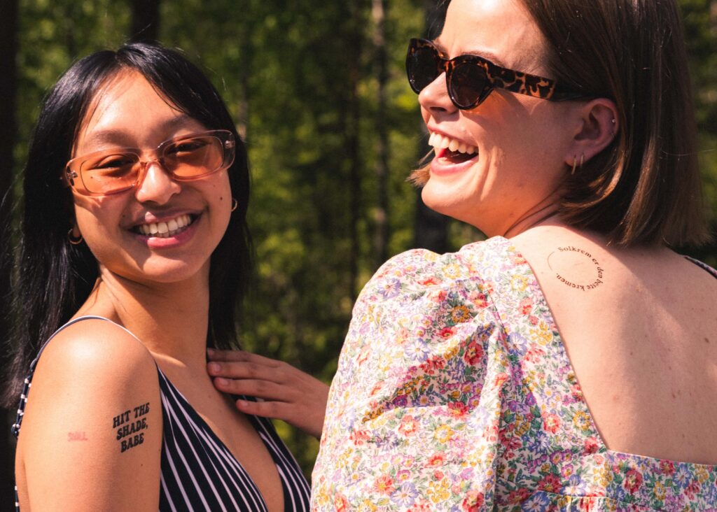 to kvinner med tatovering med solbudskap