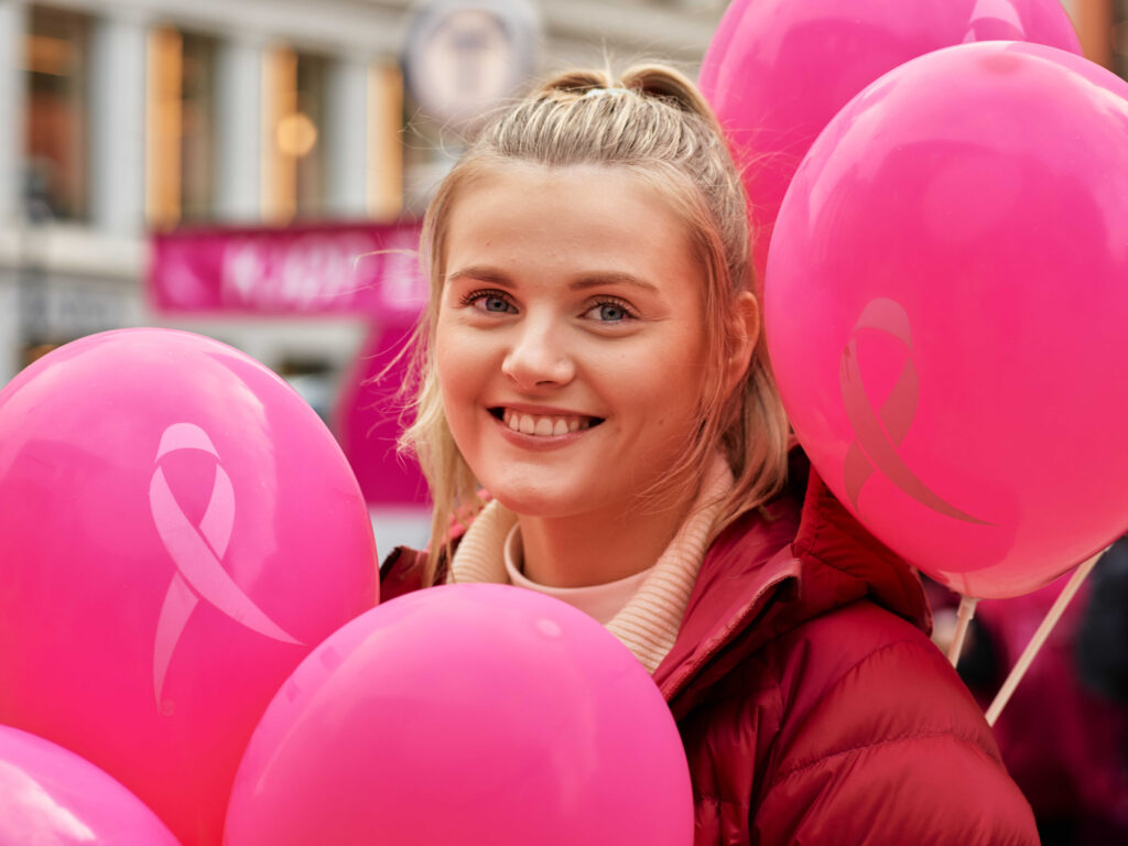 en kvinne som holder rosa ballonger på en gate.