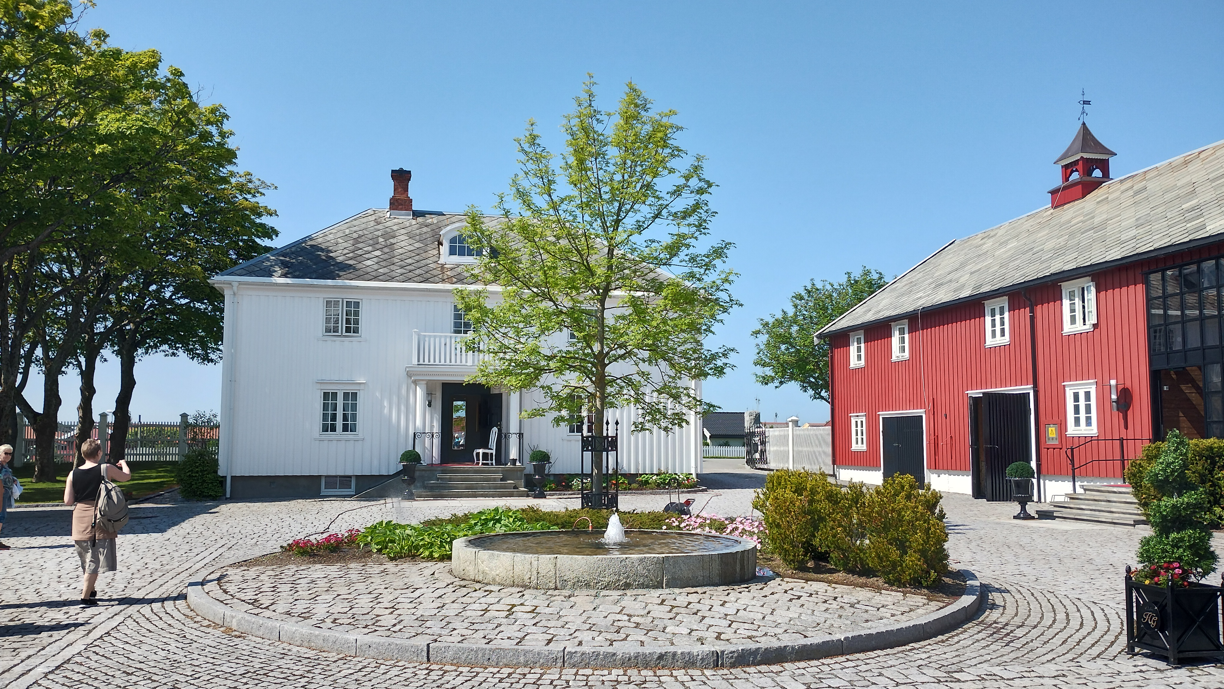 et rødt og hvitt hus med en fontene på gårdsplassen.