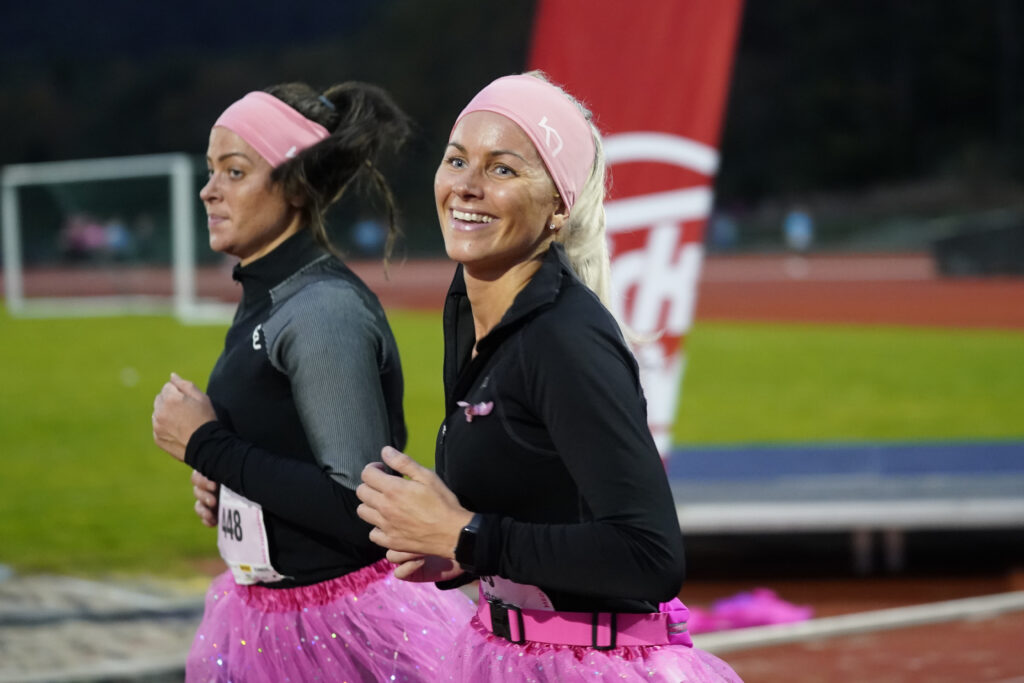 To kvinner i rosa tutuer som løper på en bane.