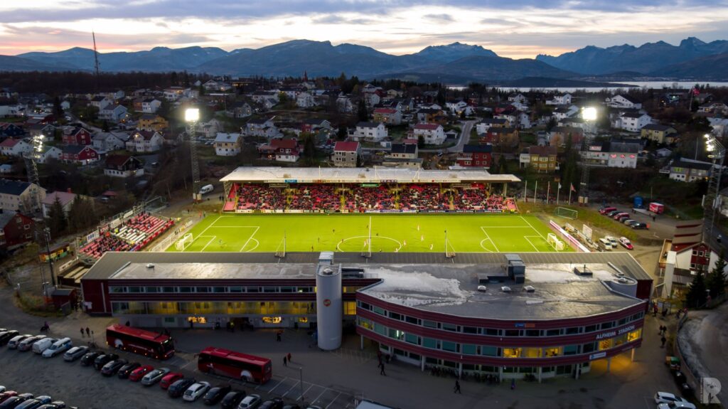 En luftfoto av en fotballstadion med fjell i bakgrunnen.