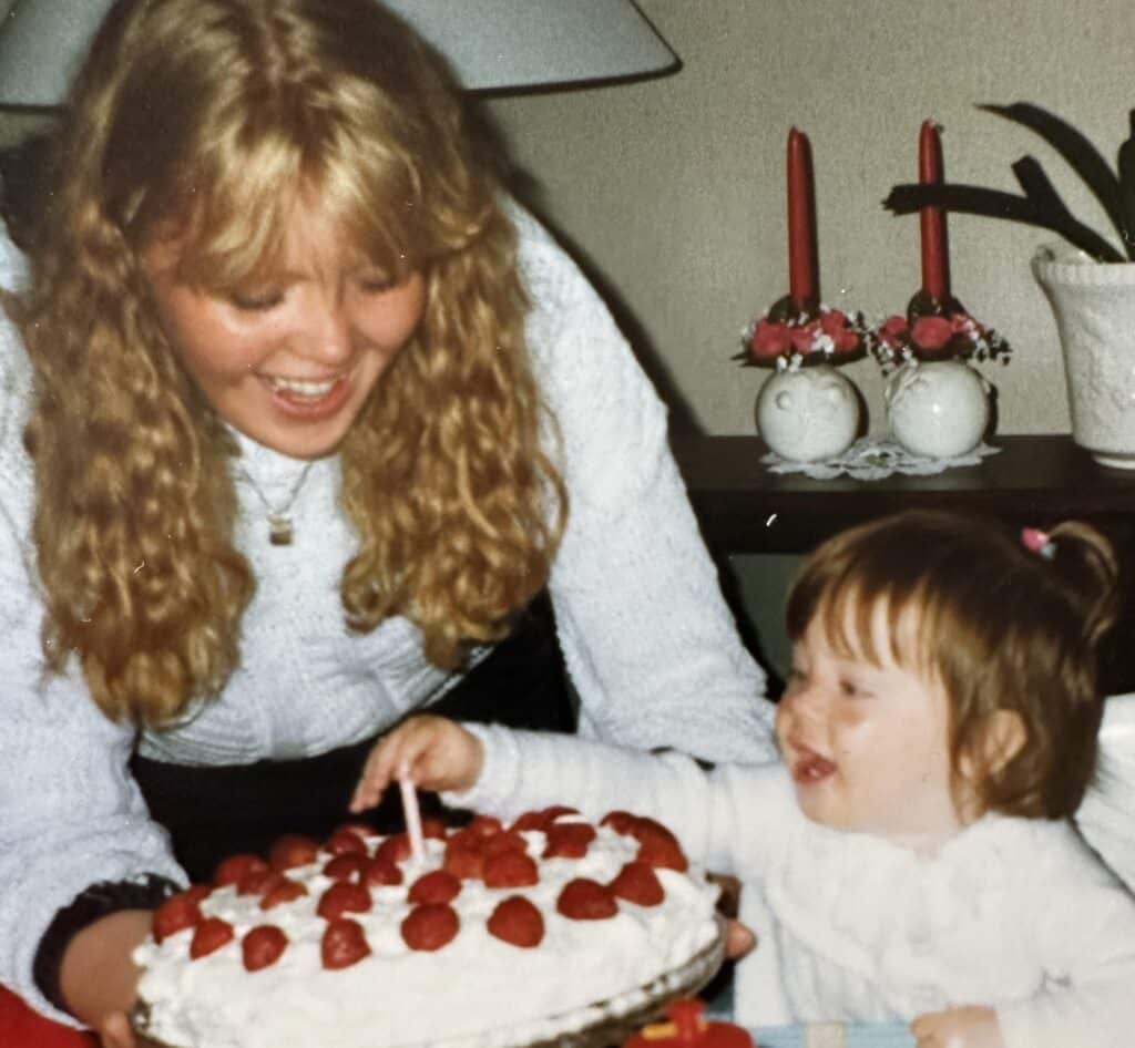 En kvinne med blondt hår blåser et lys på en kake.