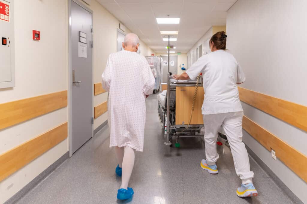 En sykepleier og en pasient går ned en gang på et sykehus.