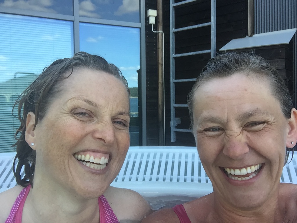 To kvinner smiler mens de sitter i en badestamp.
