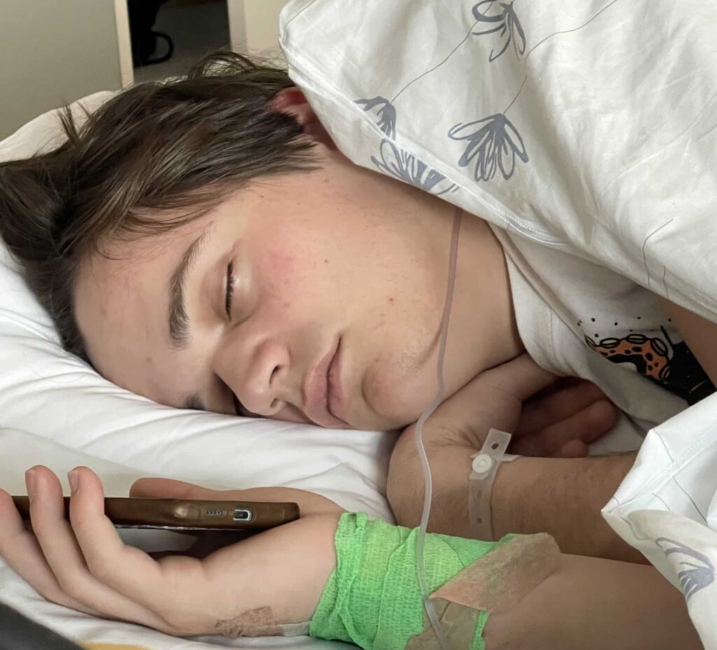 En ung mann sover i en sykehusseng.