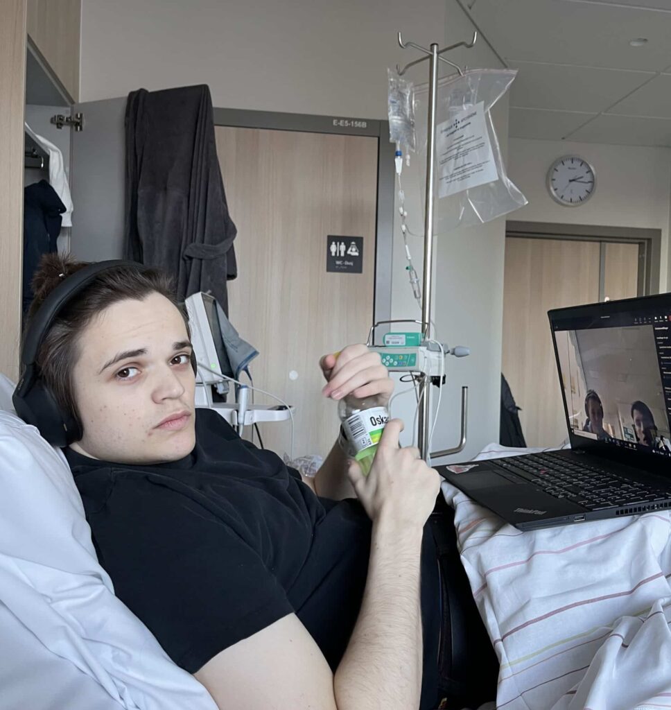 En mann i en sykehusseng med en bærbar datamaskin på fanget