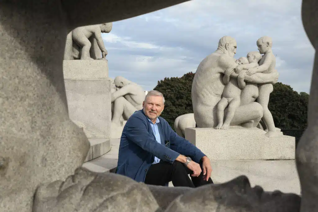 En mann som sitter på en steinbenk foran en gruppe statuer.