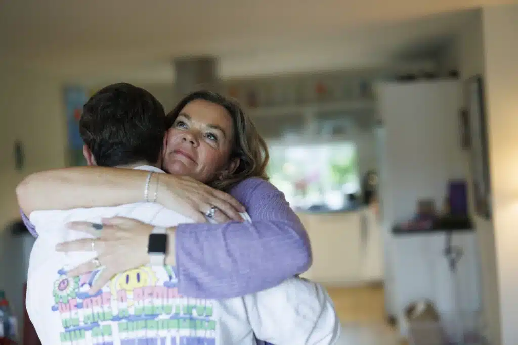 En mor klemmer sin sønn i en stue.