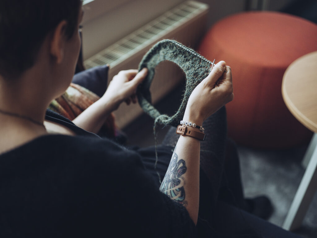 Kvinne som sitter med strikketøy i hendene