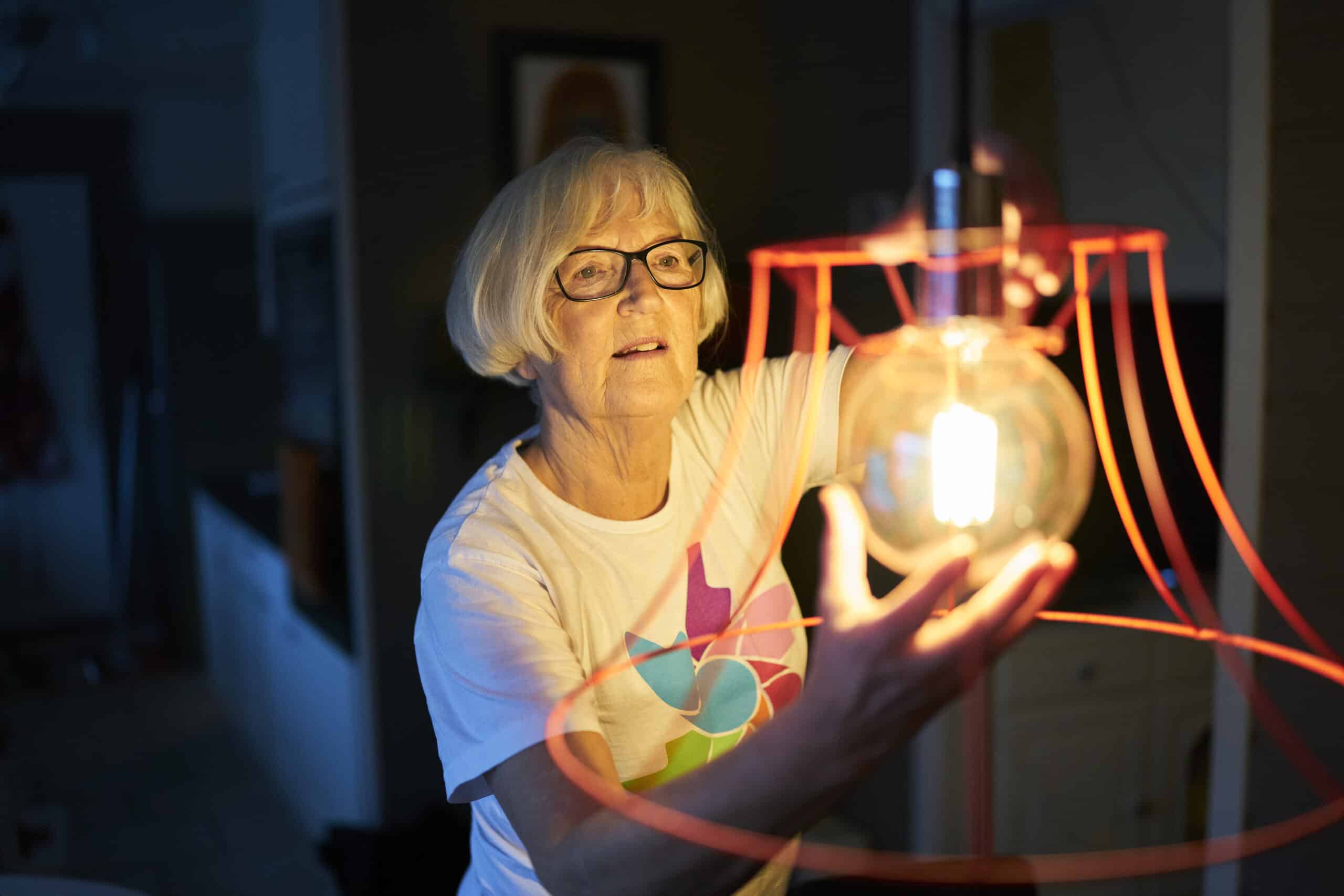 En kvinne holder en lyspære i hjemmet sitt.