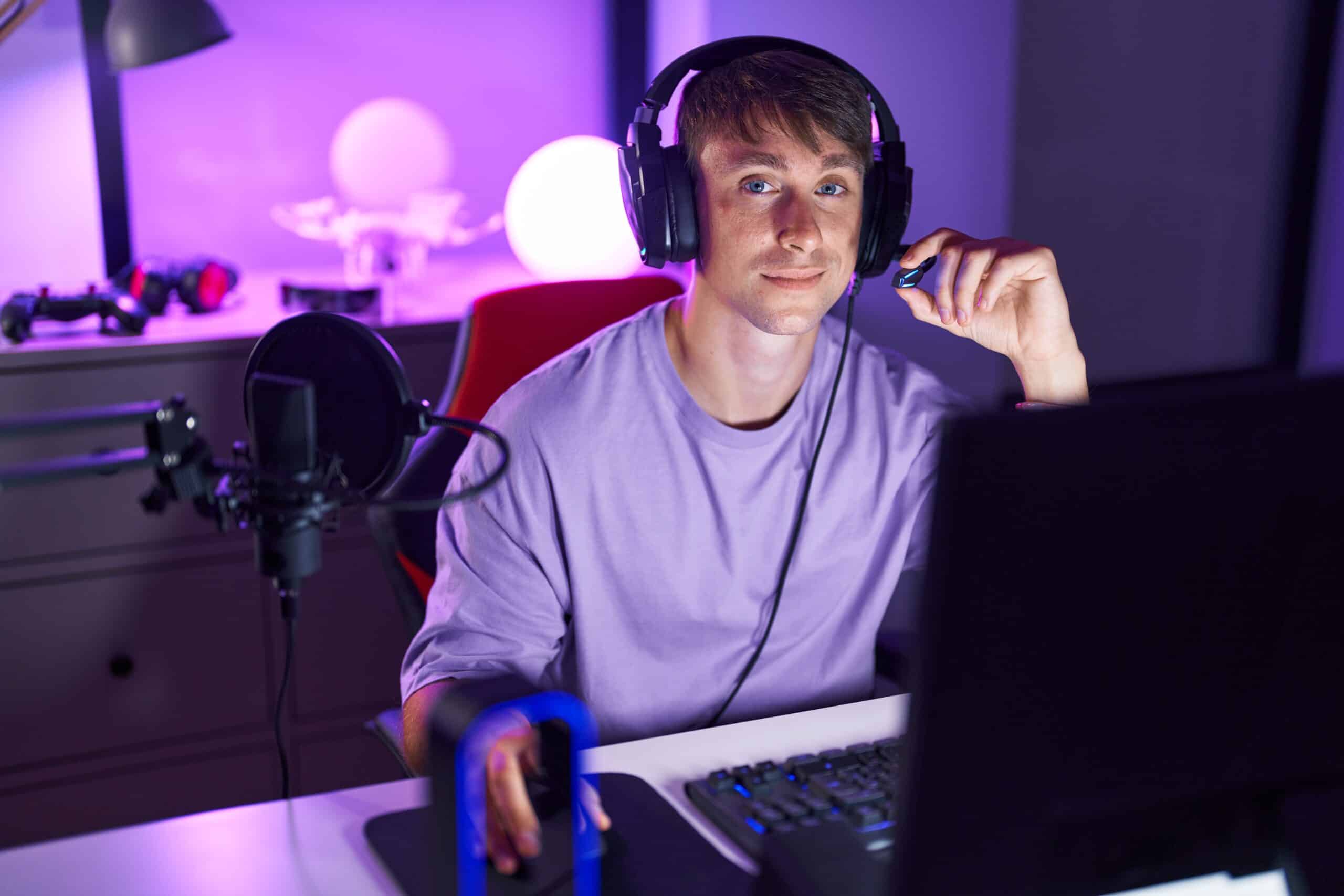 En ung mann med hodetelefoner sitter ved en datamaskin.