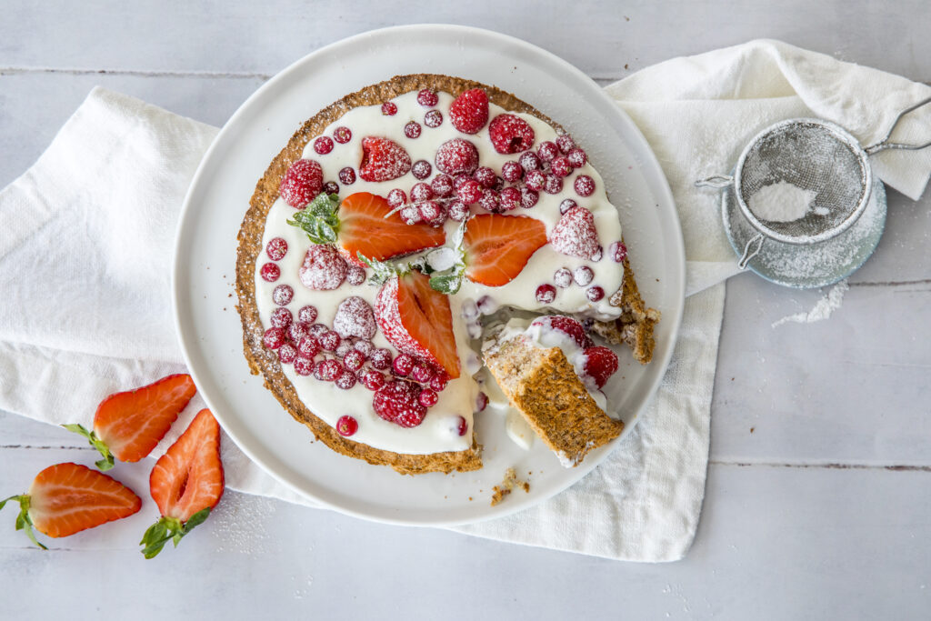 En kake med jordbær og krem på en hvit tallerken.