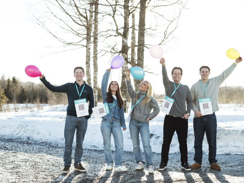 En gruppe mennesker holder ballonger i snøen.