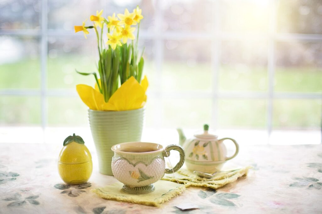 Påskeliljer og en kopp te på et bord foran et vindu.