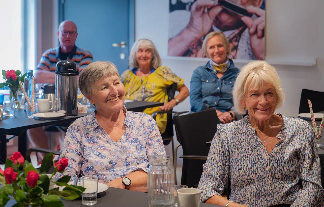 Flere mennesker sitter og lytter til foredrag