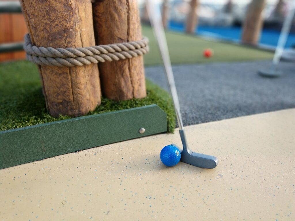 Minigolfputter på linje med en blå ball på en puttingbane.