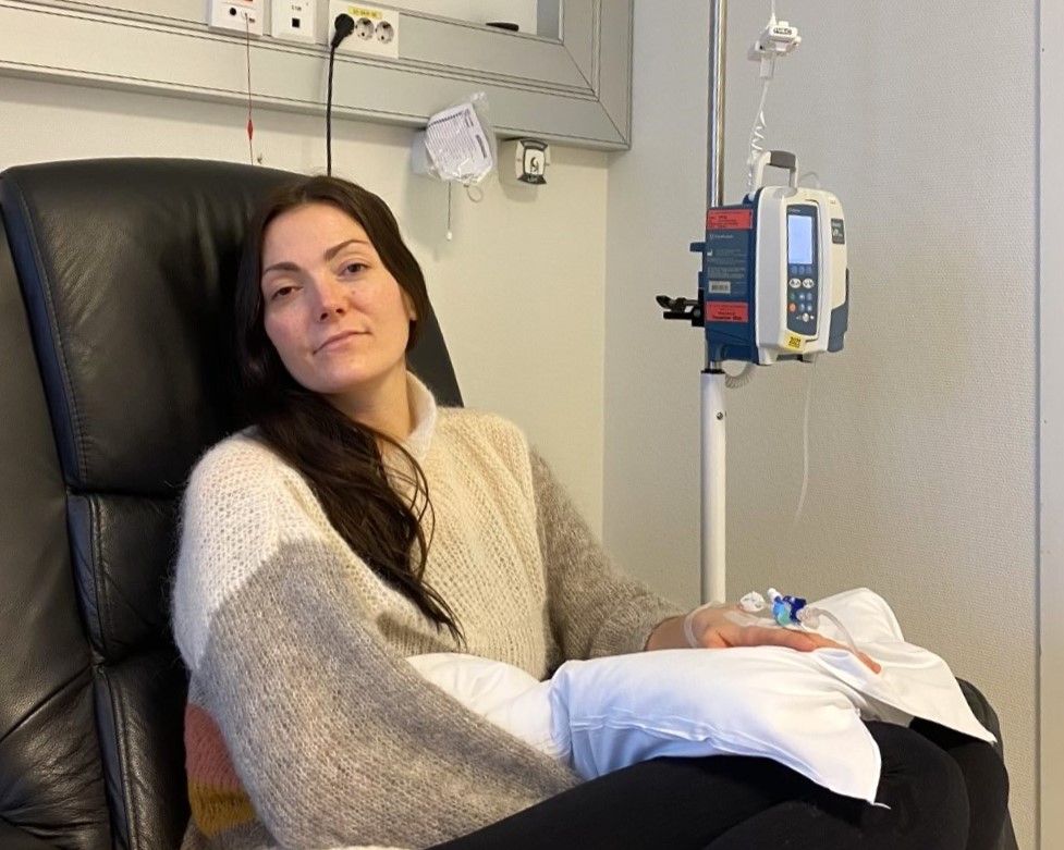 En kvinne sitter i en lenestol på et sykehus hvor hun mottar immunterapi.