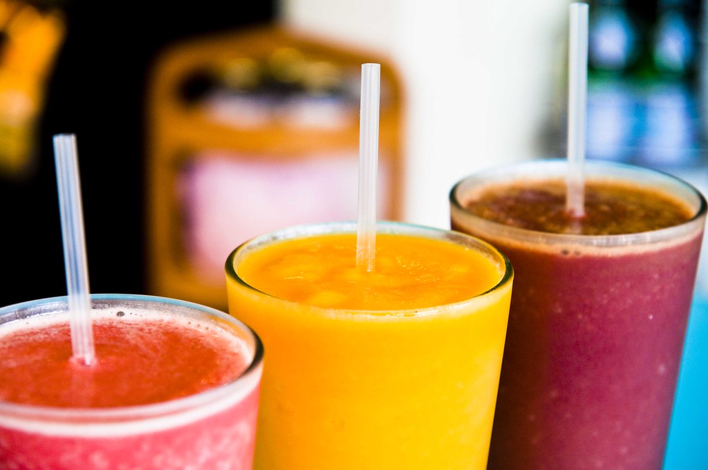 Tre fargerike smoothies: rosa, gul og lilla, hver i et klart glass med et sugerør.