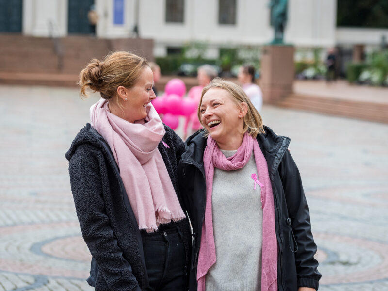 To kvinner ser på hverandre, de smiler og ler.