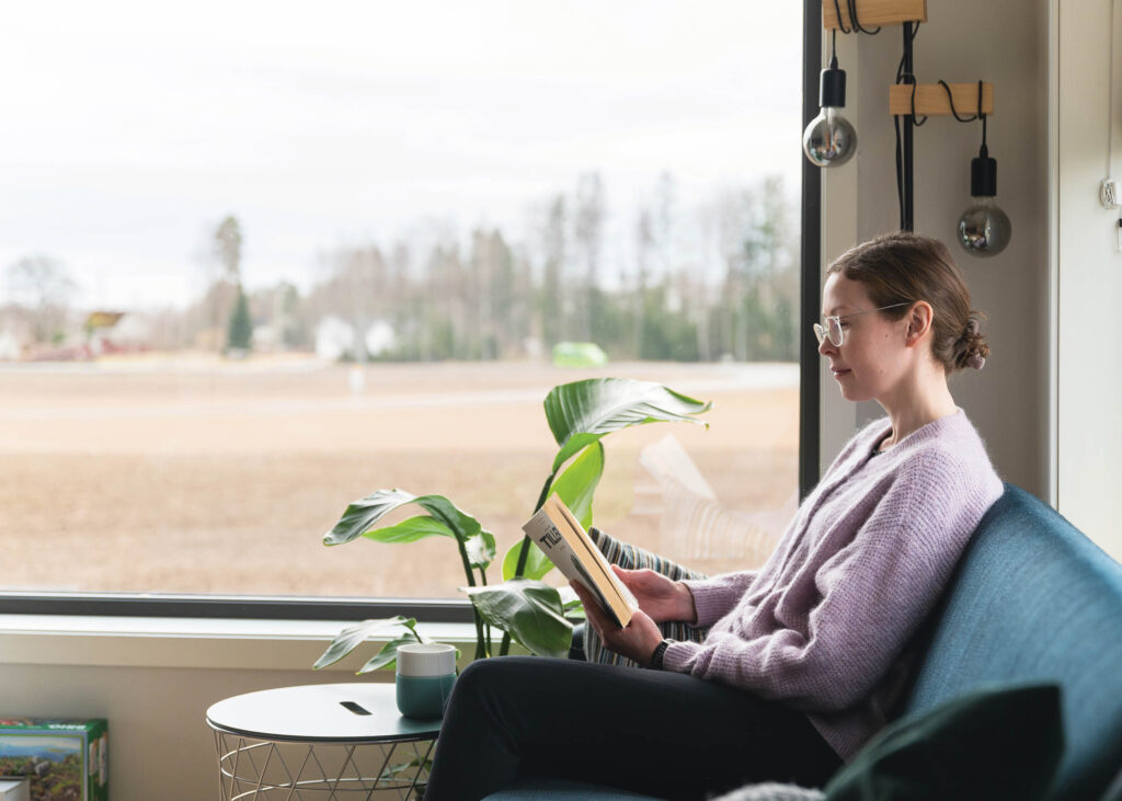 Anniken sitter i en sofa og leser en bok. 