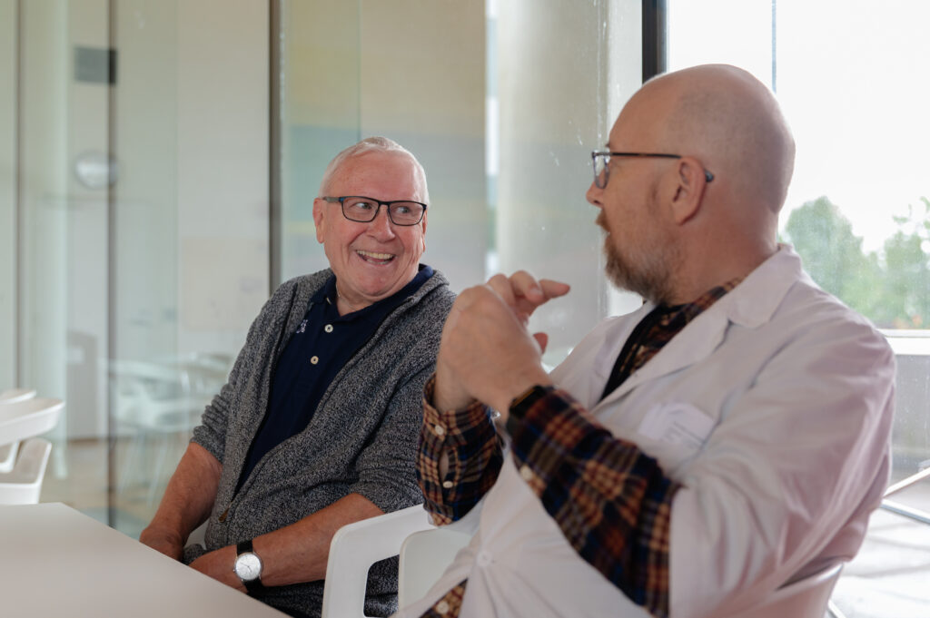 Tron og Anders Dahm, leder av den kliniske studien, smiler til hverandre under en samtale